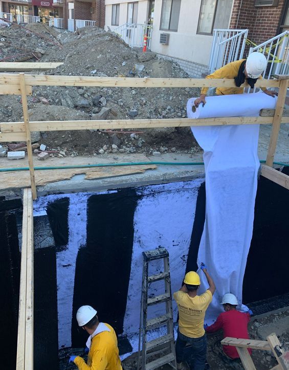 A group of workers waterproofing a wall