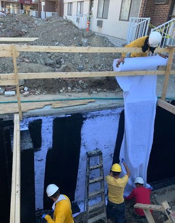 A group of workers waterproofing a wall