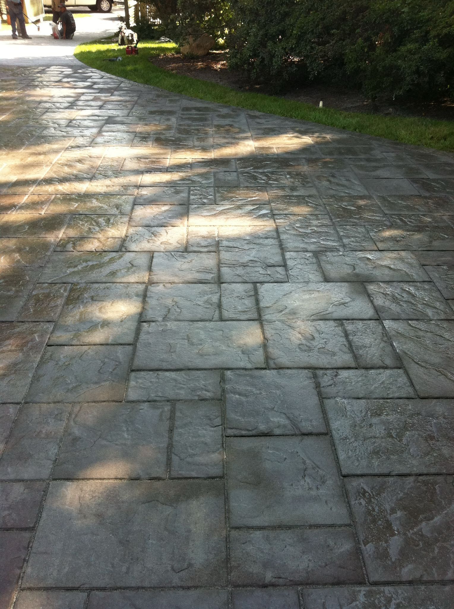 A brick walkway leading to a grassy area with trees in the background