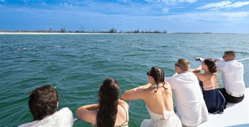 a group of people are sitting on the back of a boat looking at the ocean