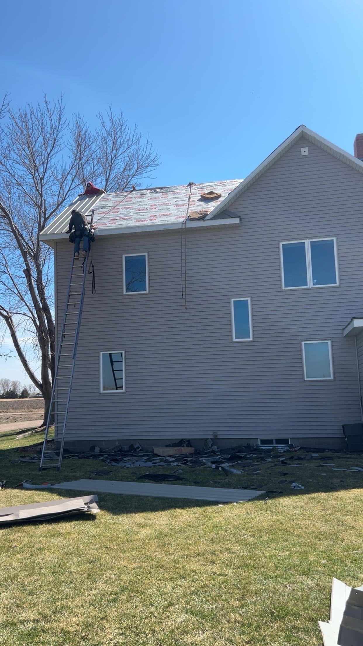 Damaged beige house with torn roof and broken siding on a sunny day