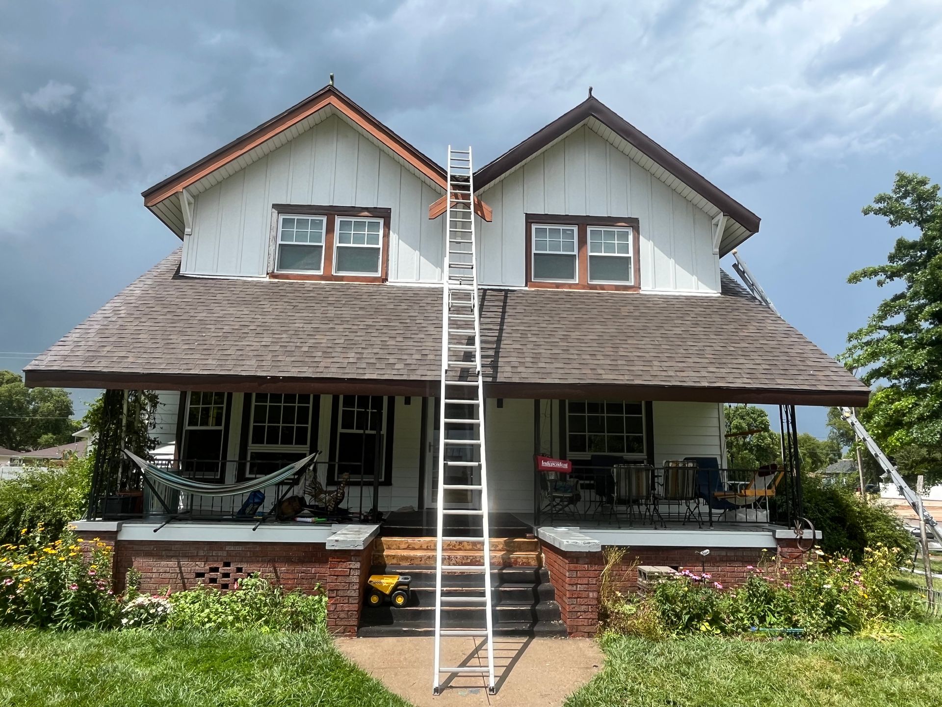 Two-story house with a steep roof and a ladder leaning to the upper center window