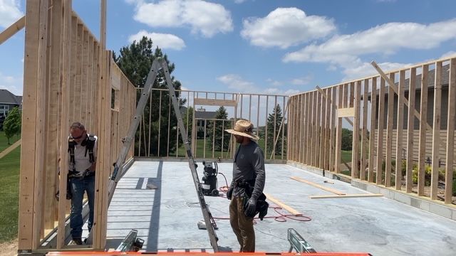Construction workers framing the walls of a house on a sunny day