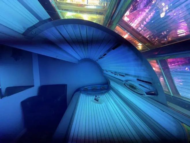 Futuristic blue-lit sauna or relaxation room with curved bench seating and glowing ceiling panels