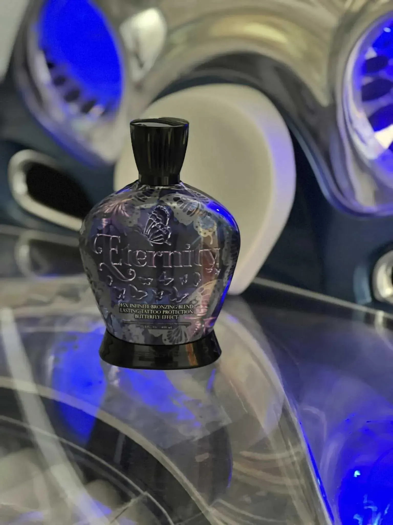 Bottle of tanning lotion with blue accents, on a reflective surface with a blue background.