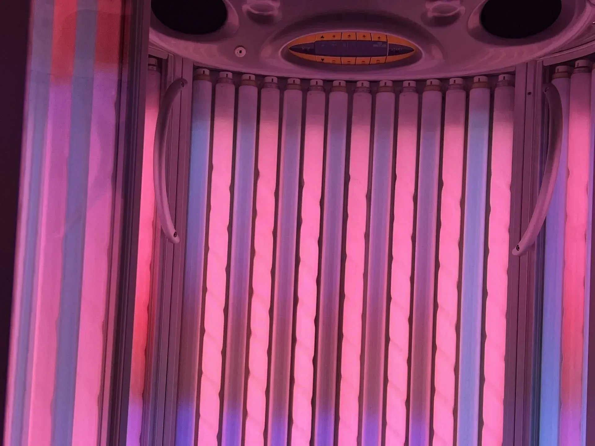 Tanning bed interior, glowing pink and blue tubes.