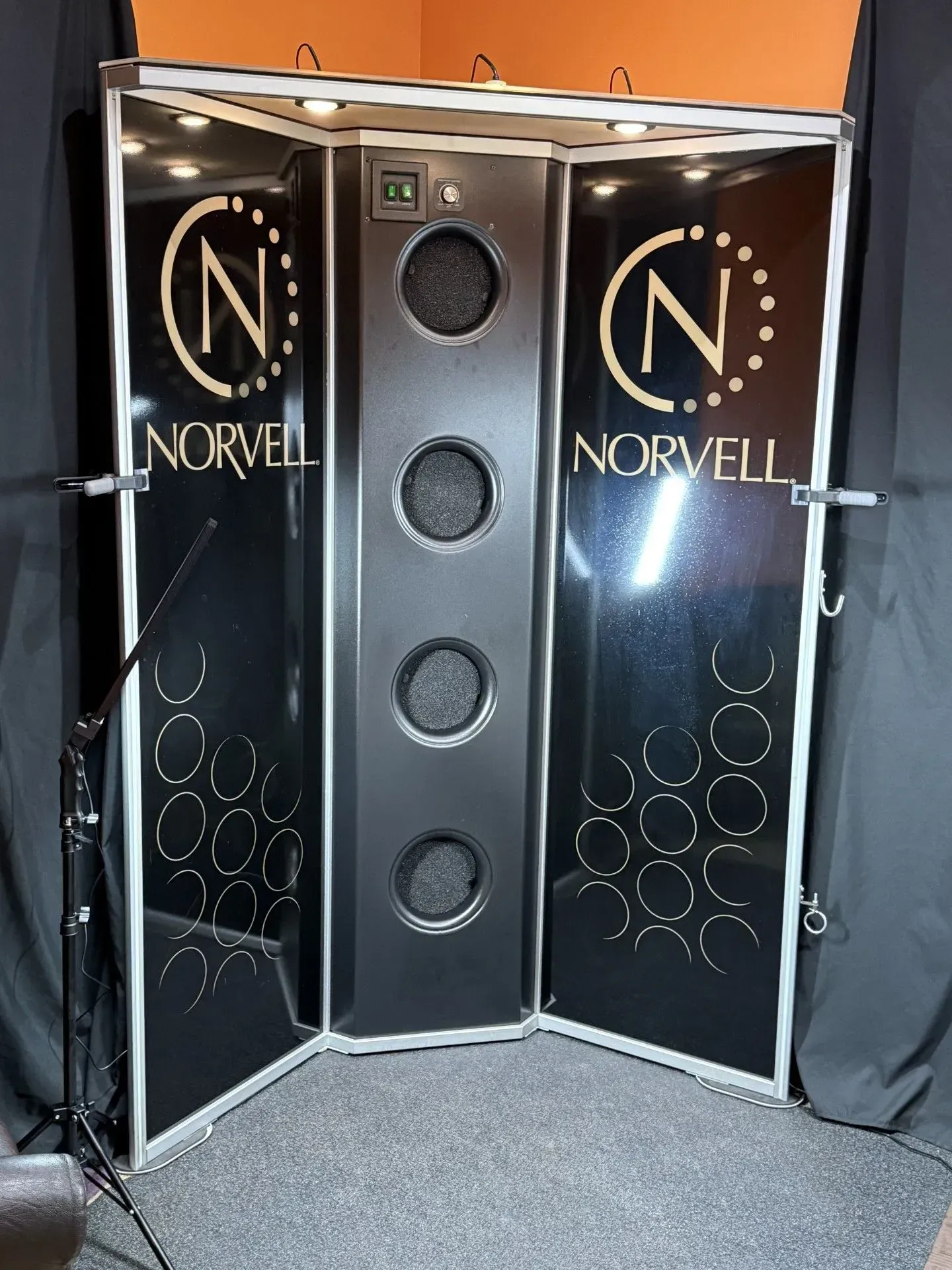 Norvell spray tanning booth, black and silver, with logo on doors.