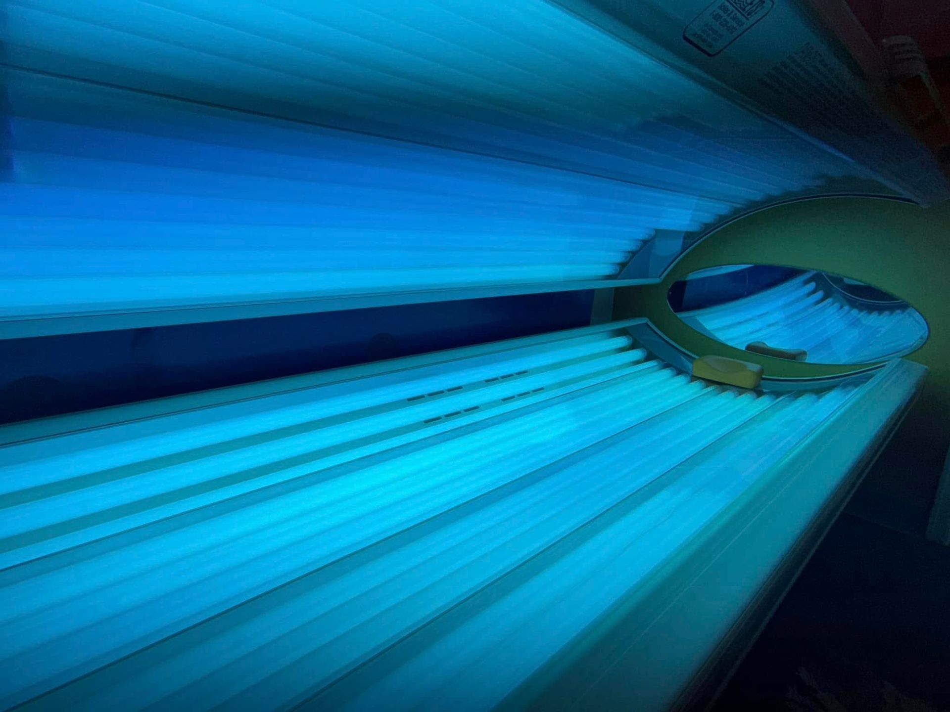 Tanning bed interior with blue UV lights, ready for use.