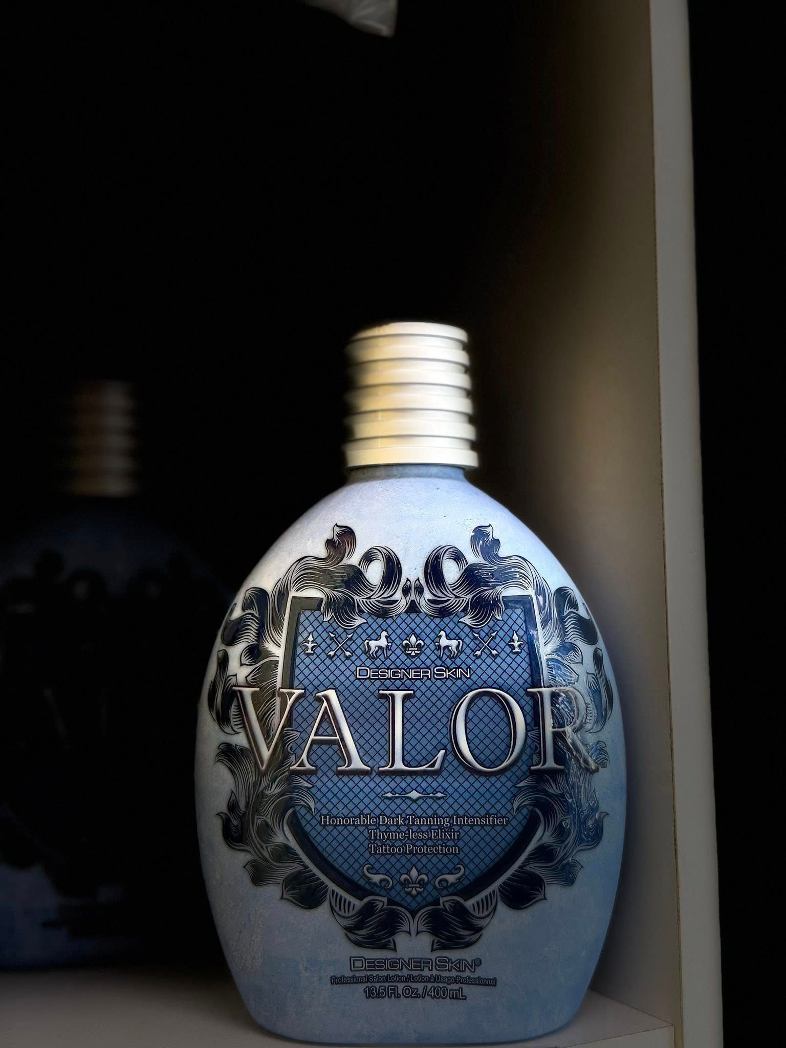 Blue, oval-shaped Valoi bottle with silver cap and ornate label, lit by a beam of light in a dark setting.