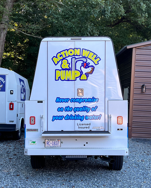 The rear of a white service van labeled "Action Well & Pump" with a rooster logo and the text "Never compromise...".
