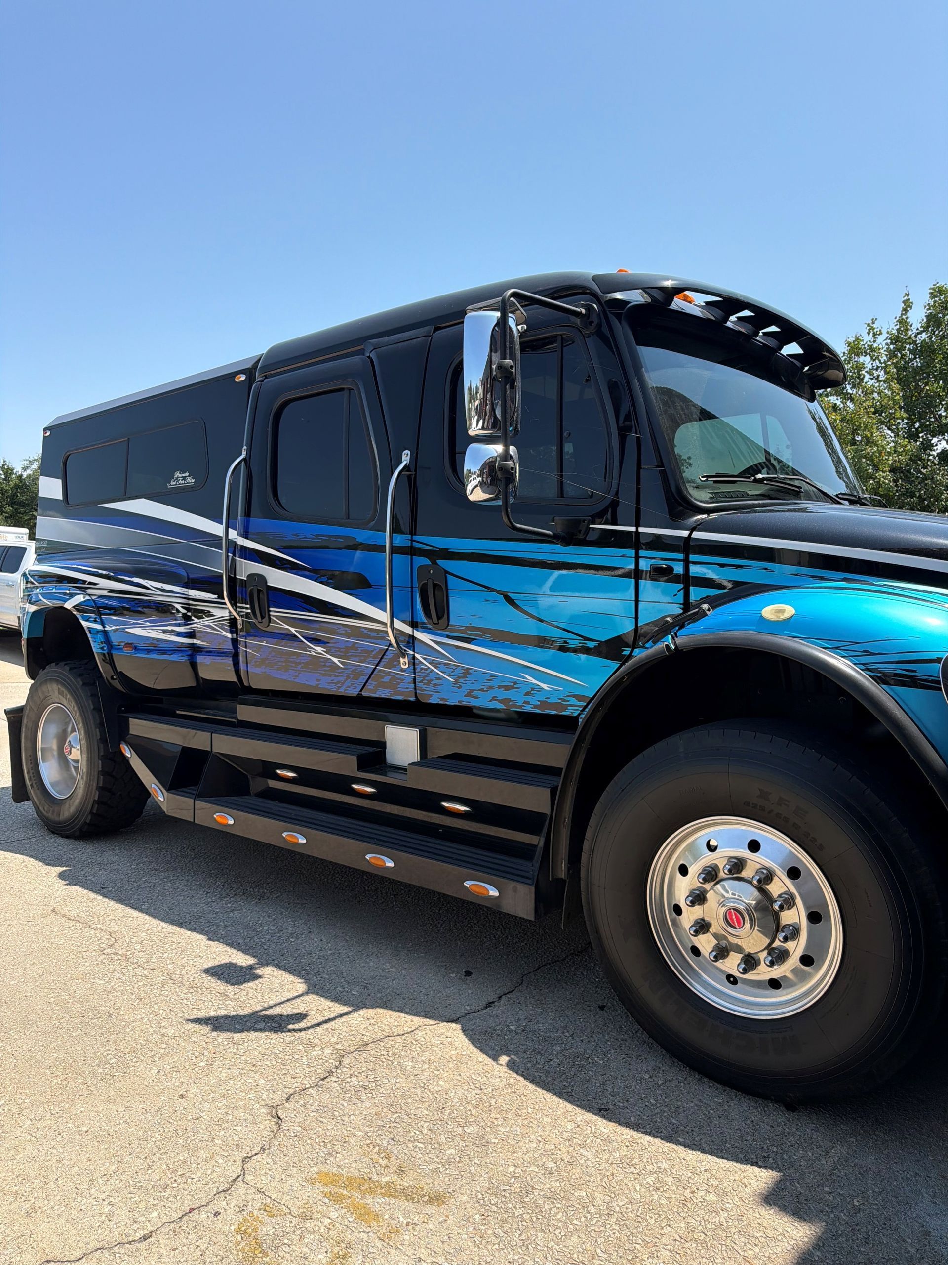 Black and blue stretched limousine parked on a sunny street, side view.
