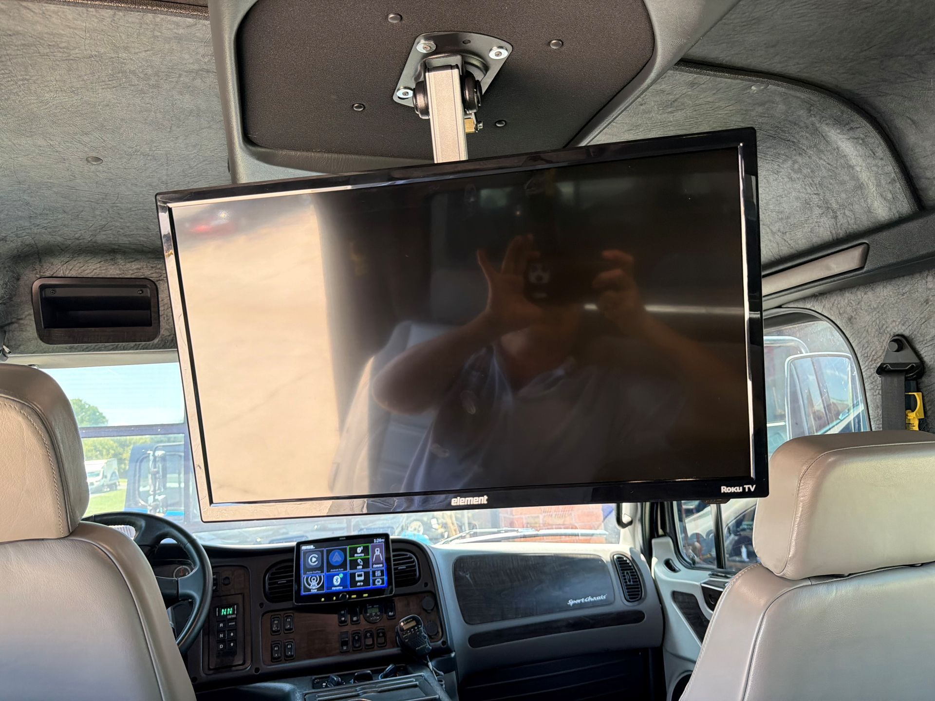 Large flat-screen TV mounted inside a vehicle, facing the front seats.