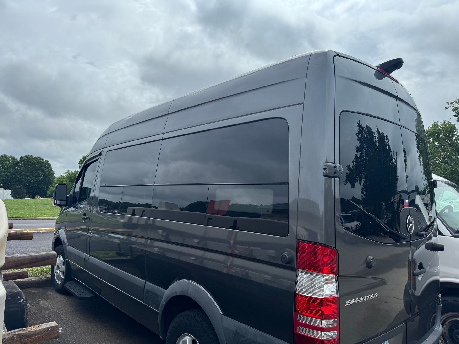 Black passenger van parked beside a road under cloudy skies