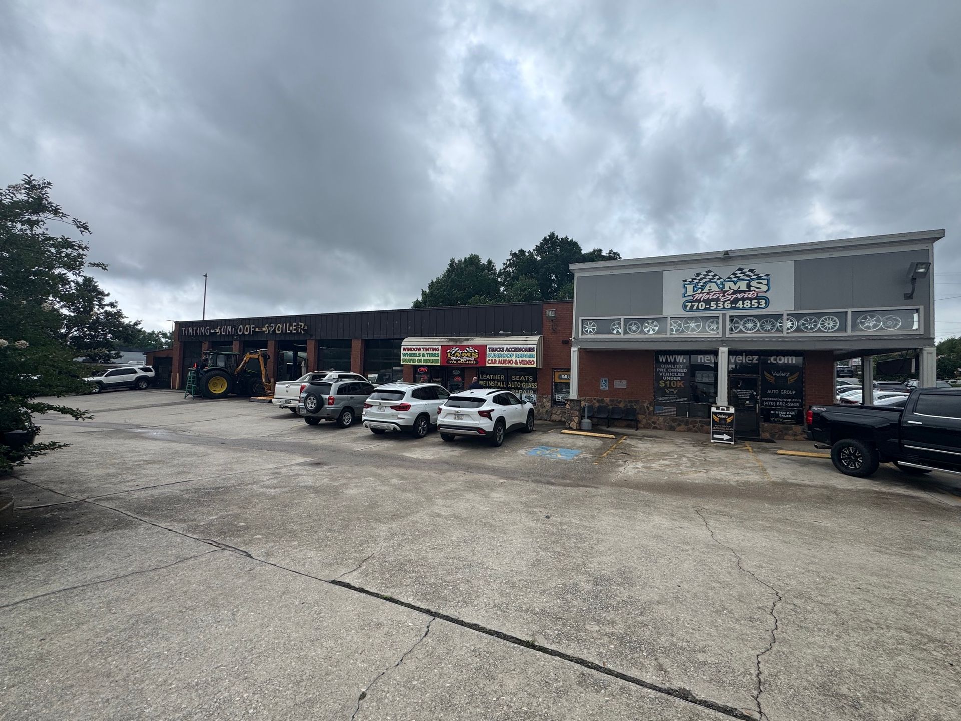 Auto repair shop with parked cars under a cloudy sky