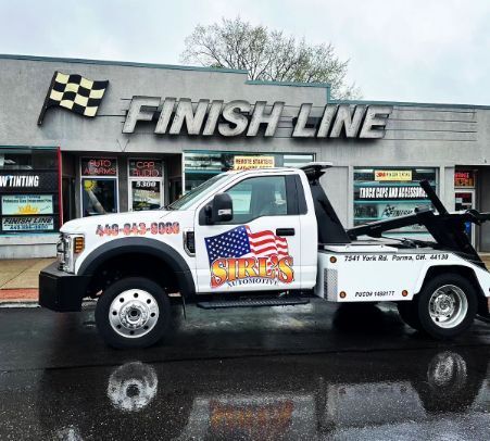 White tow truck parked outside Finish Line store on a rainy day