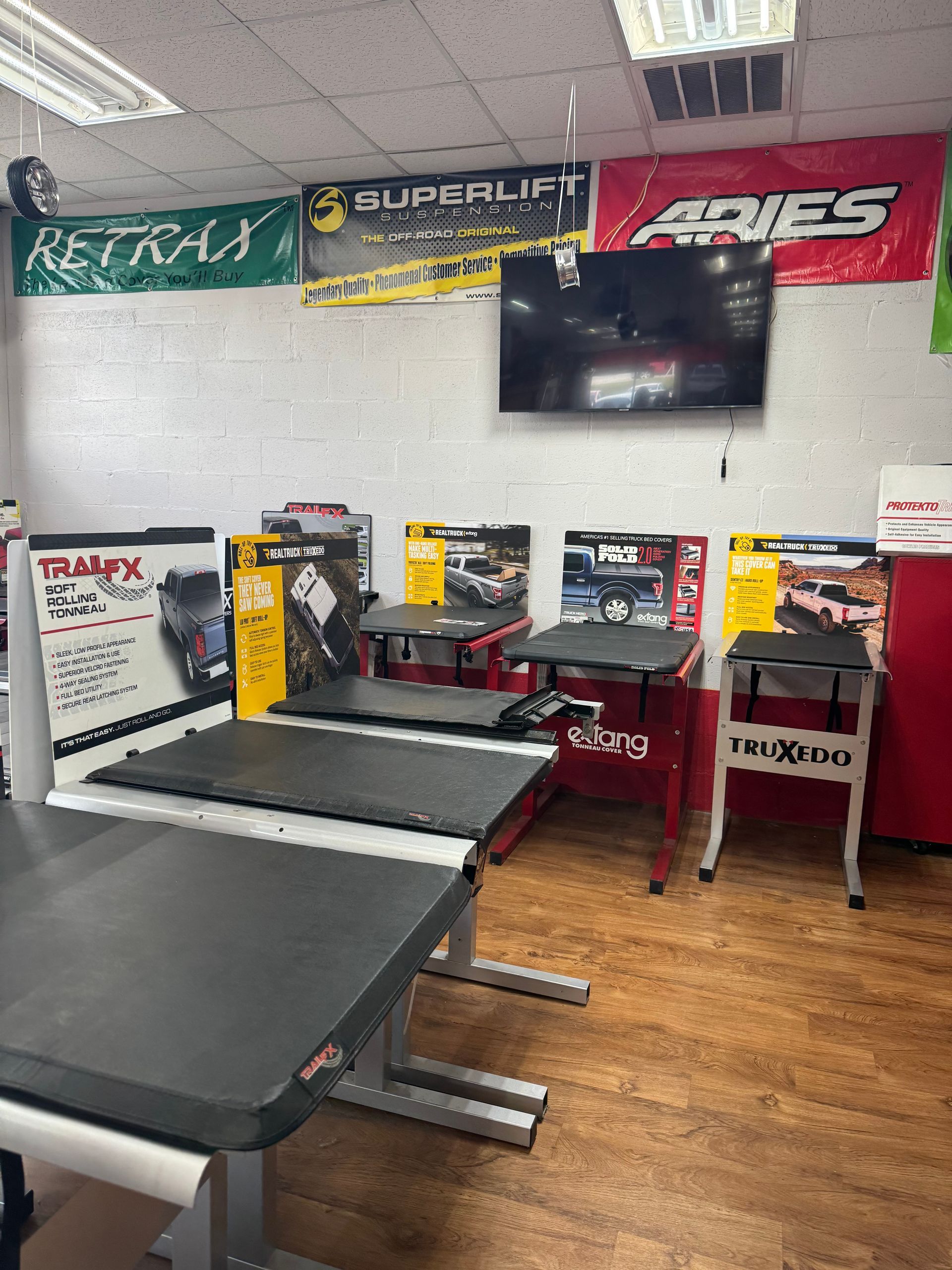 Small retail shop interior with ATV parts, tool displays, and branded banners on the walls.