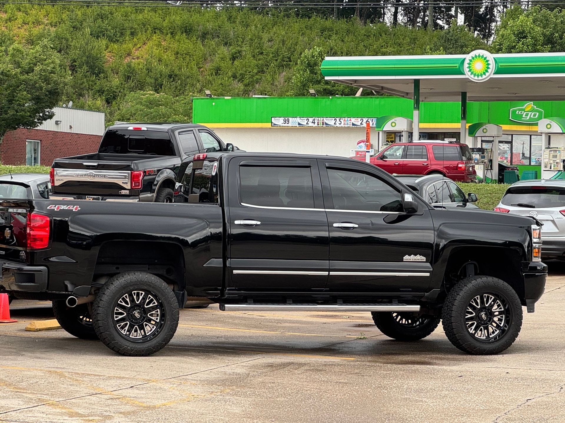 Black lifted pickup truck parked at a gas station with other vehicles nearby