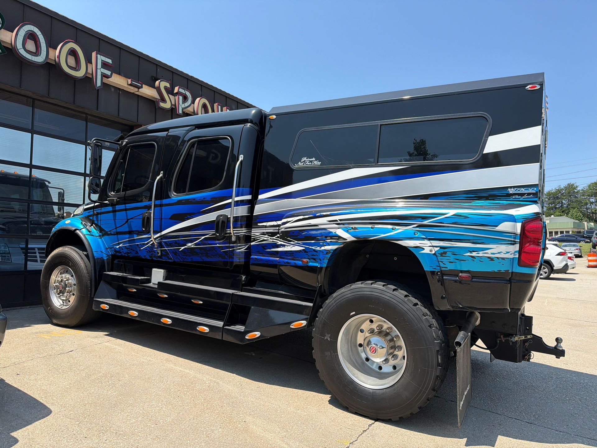 Blue and black lifted pickup truck parked outside a dealership building