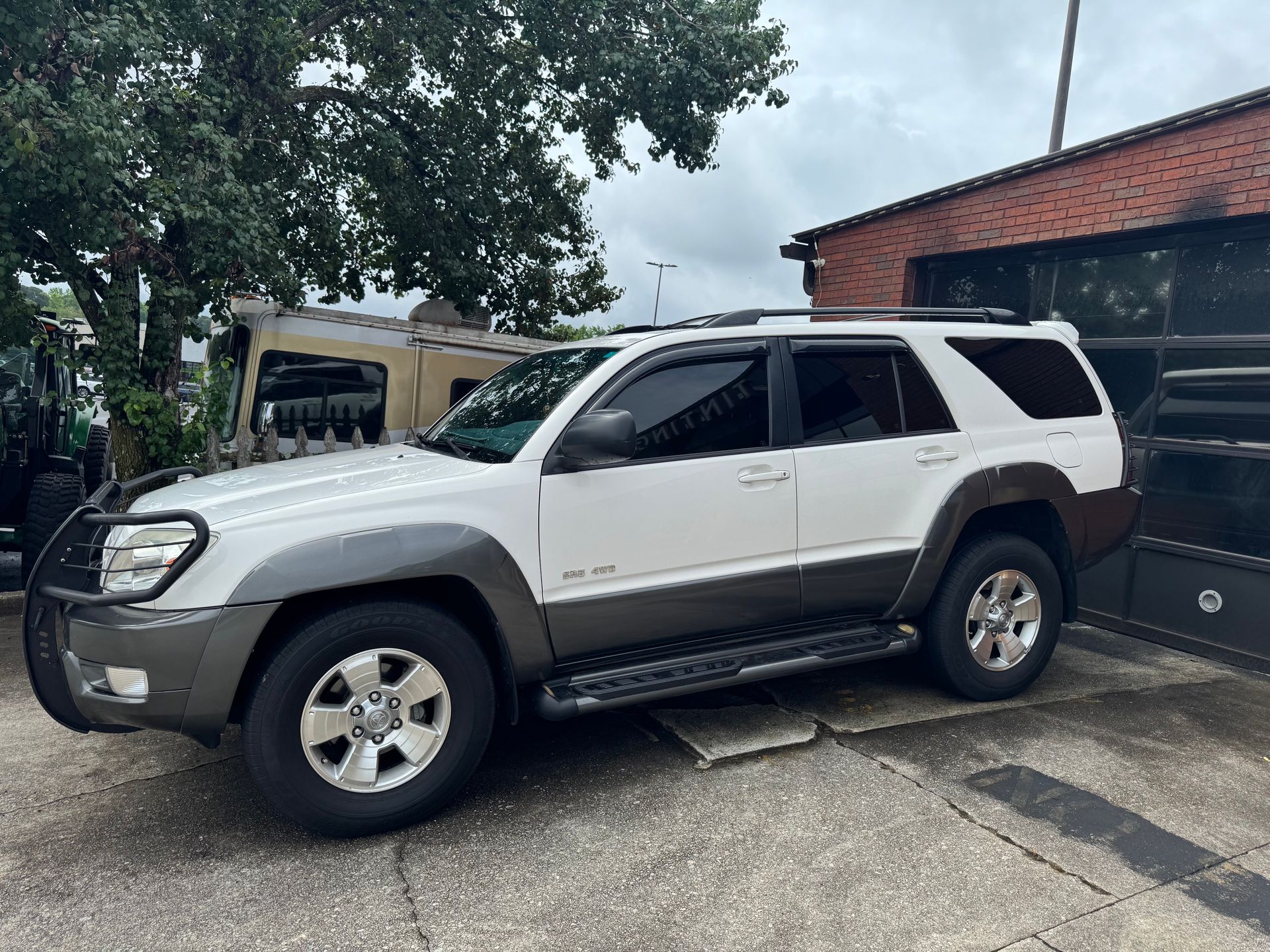 White SUV parked outdoors beside a building and trees
