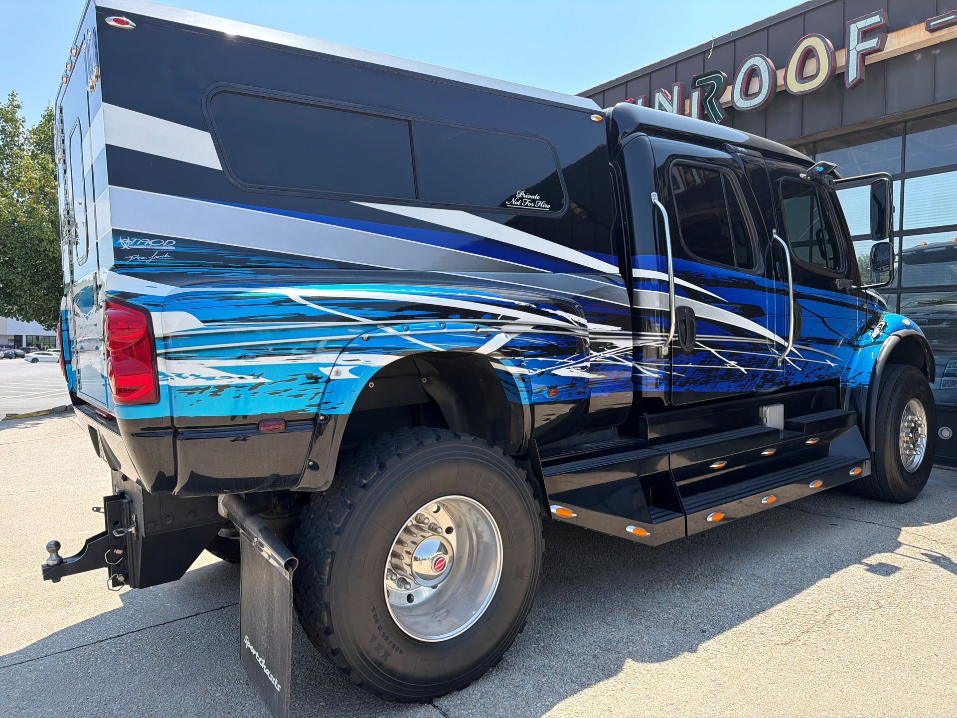 Blue and black lifted pickup truck parked outside a dealership on a sunny day