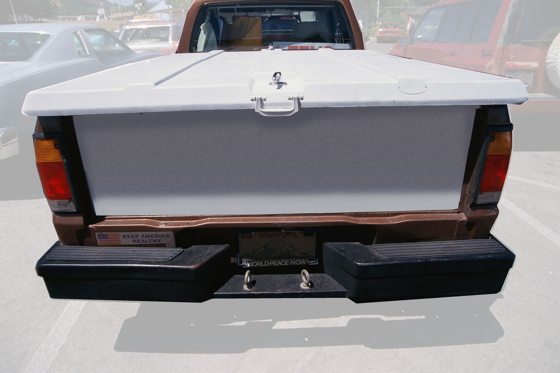 Rear view of a pickup truck with an open white tailgate and black rear bumper parked on a street