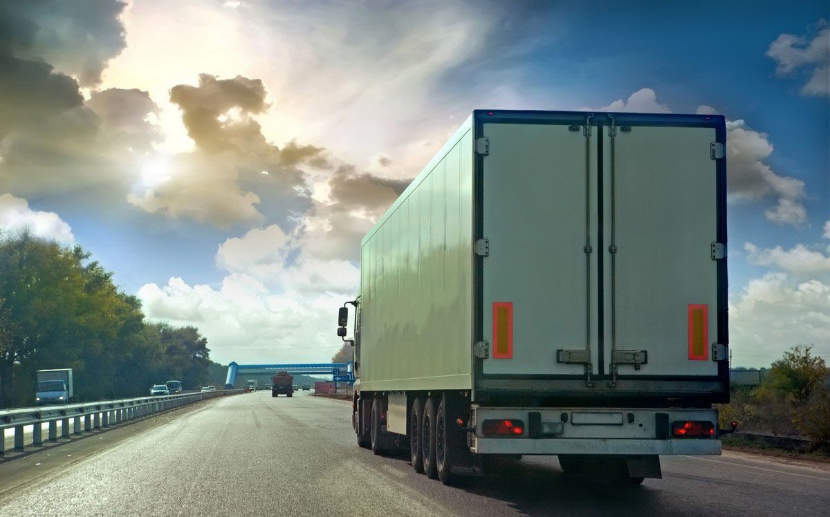 Truck driving on a highway under a cloudy sky at sunset