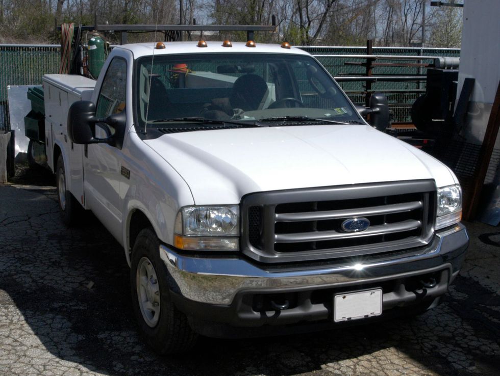White Ford pickup truck parked outdoors in a lot, front view.