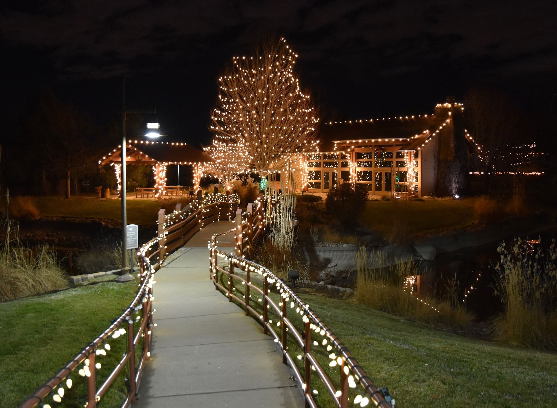 a walkway leading to a house decorated with christmas lights