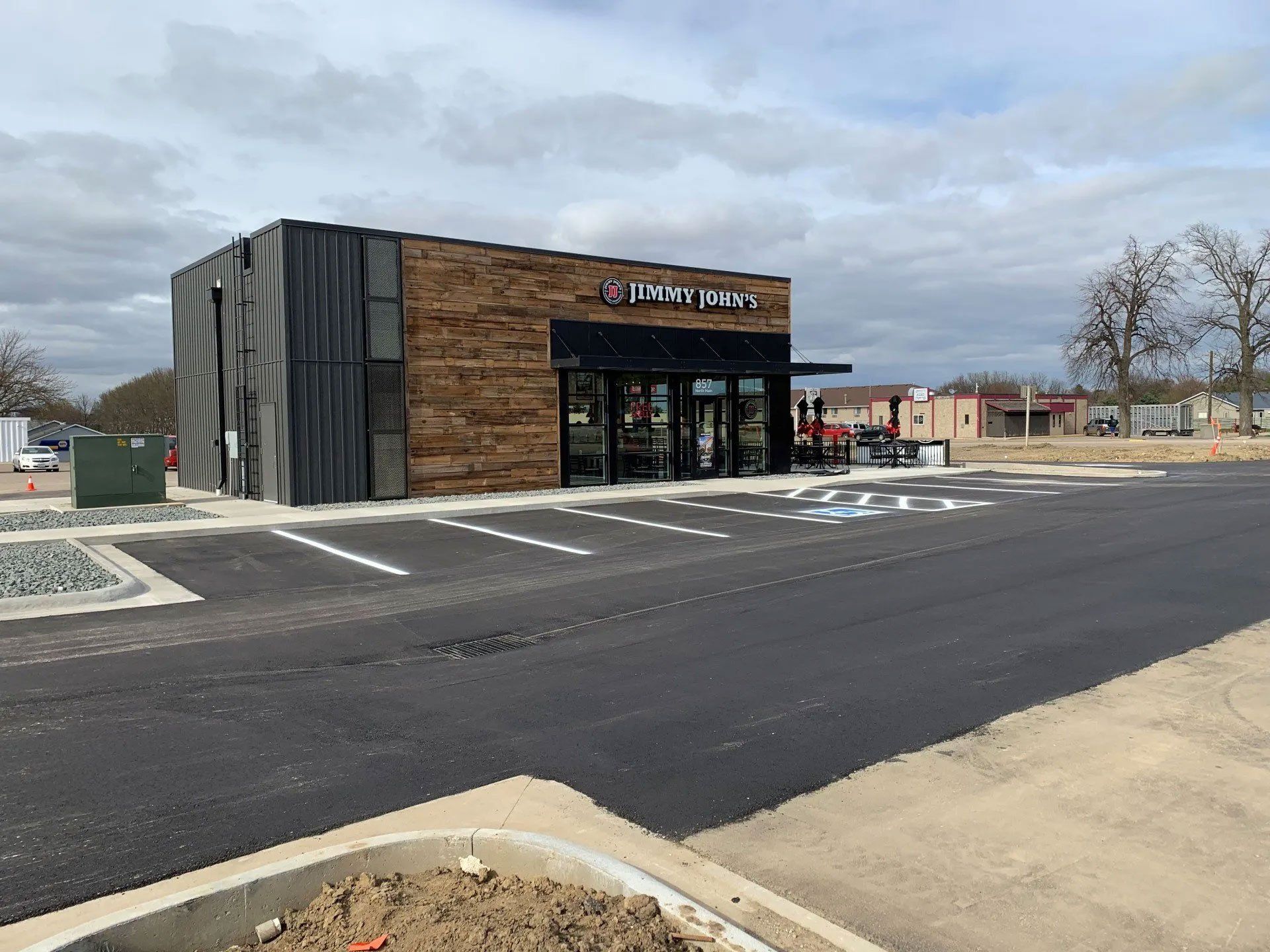 Exterior view of a newly built restaurant with a dark facade and a drive-thru, with an empty parking lot.