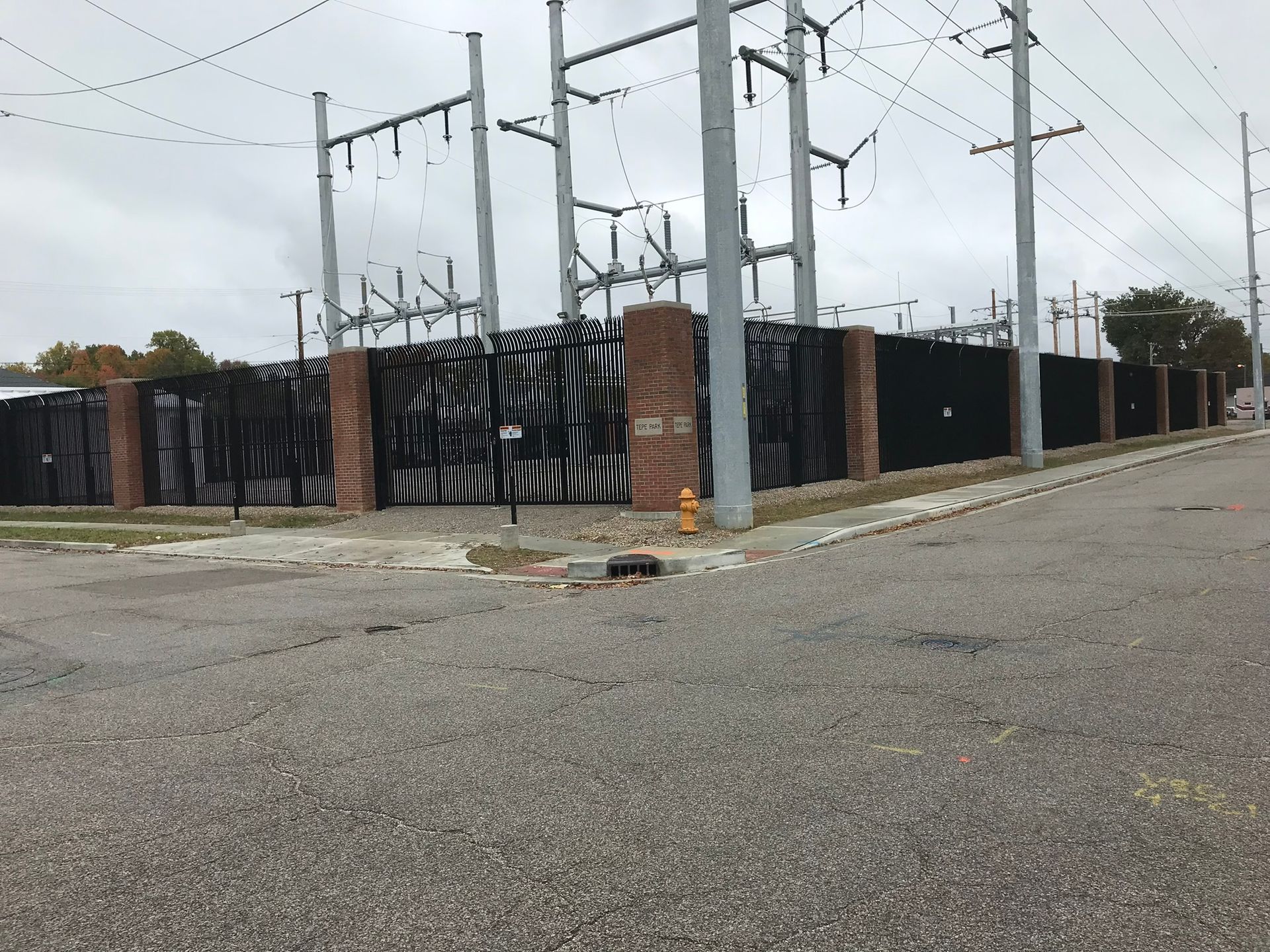 There is a fire hydrant on the side of the road in front of a power plant.