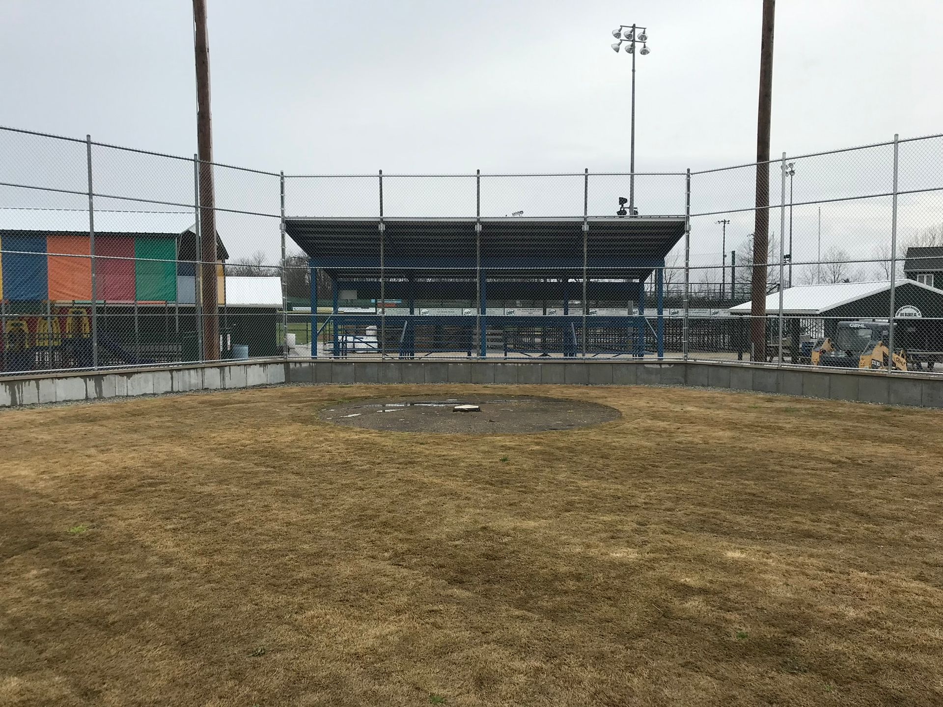 A baseball field with a fence and a stadium in the background.