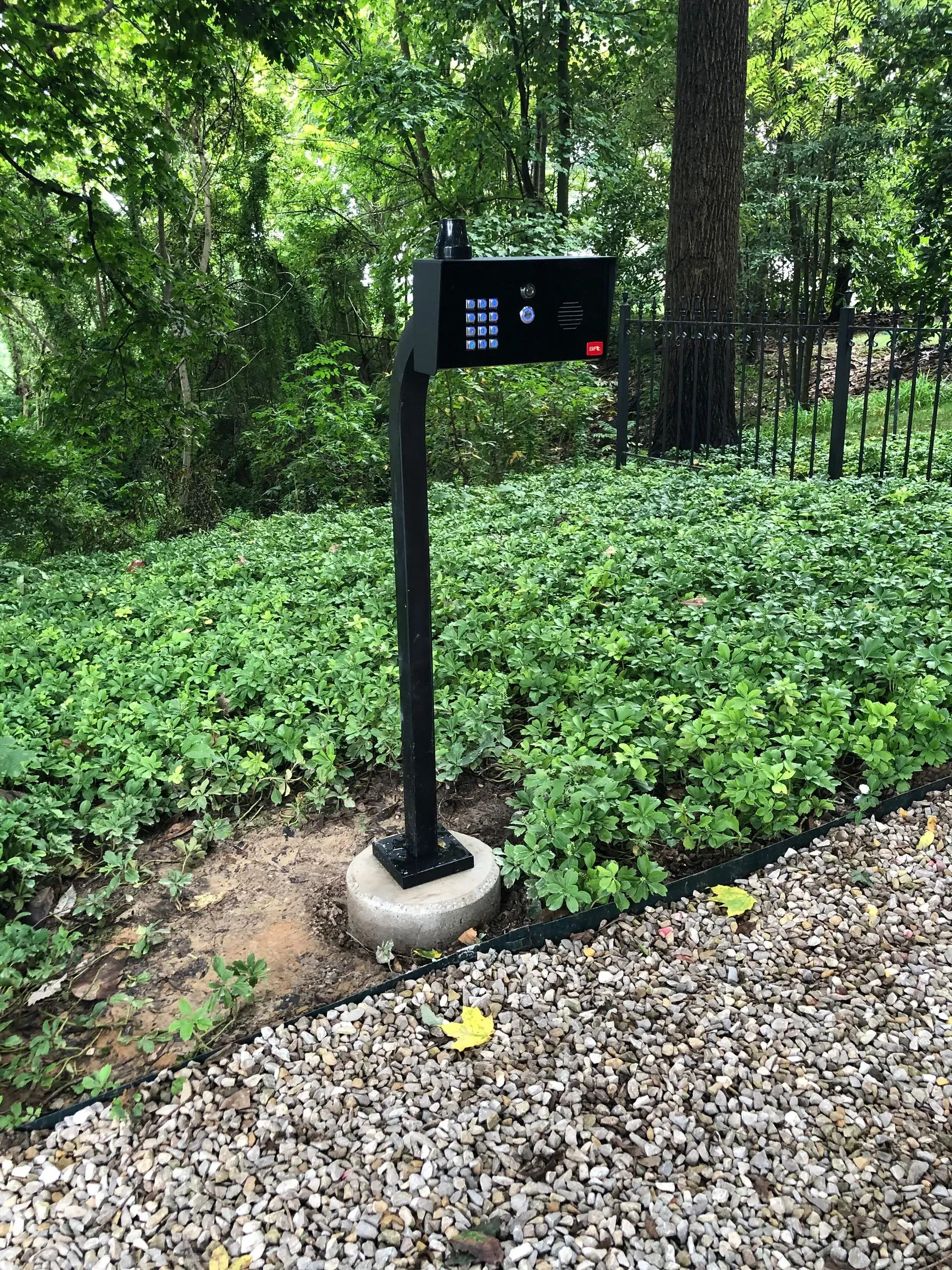 A mailbox is sitting in the middle of a gravel driveway.