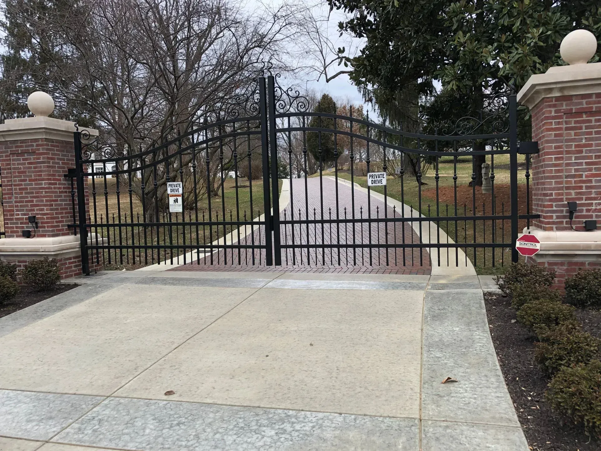 A wrought iron gate with a brick pillar in the background