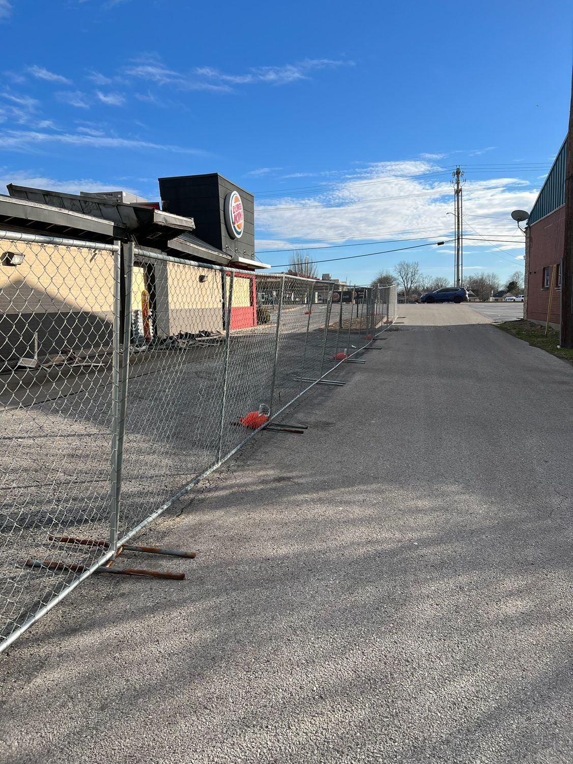 A chain link fence is surrounding a building that is being demolished.