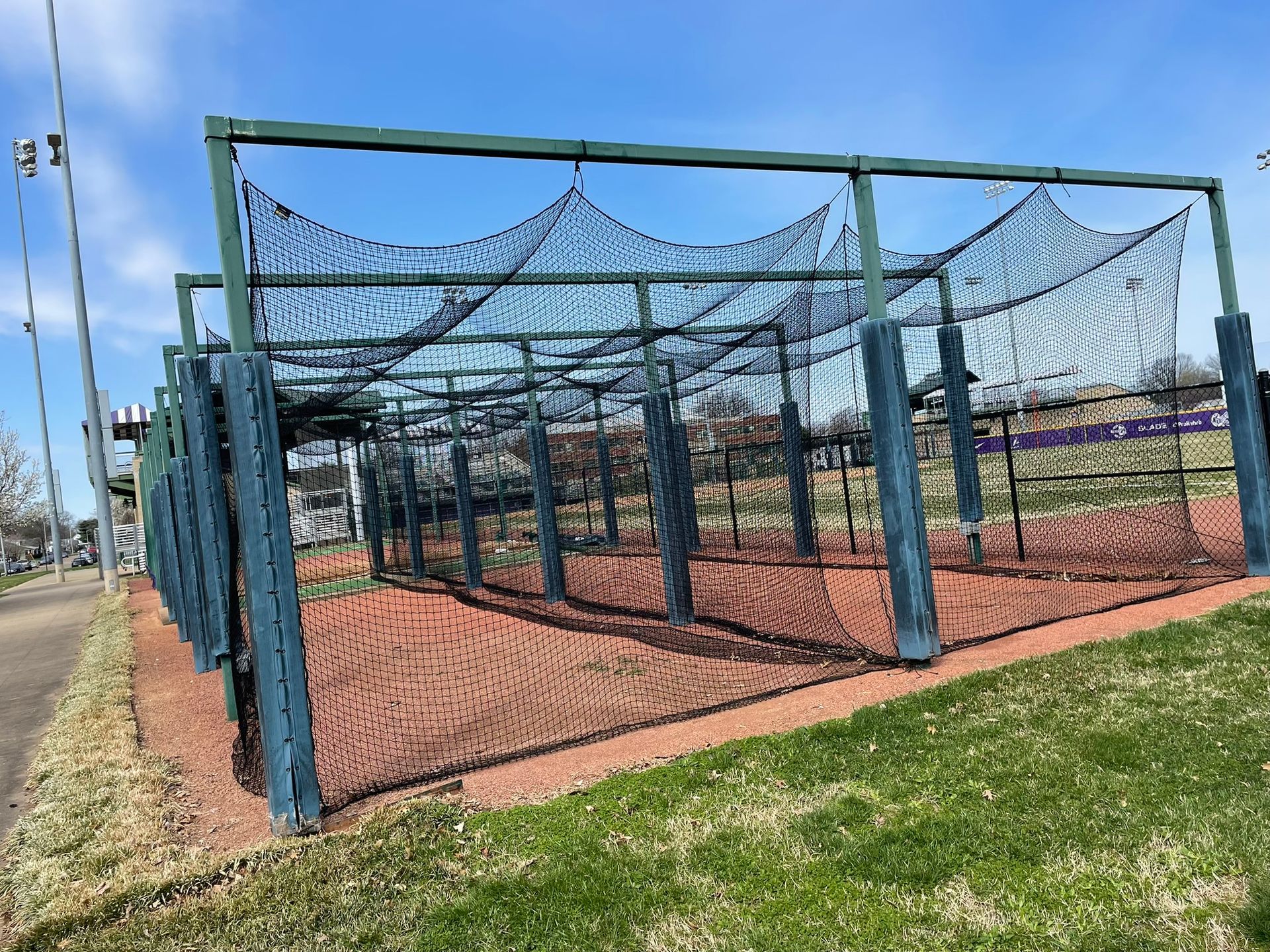 A baseball field with a fence and a net surrounding it.