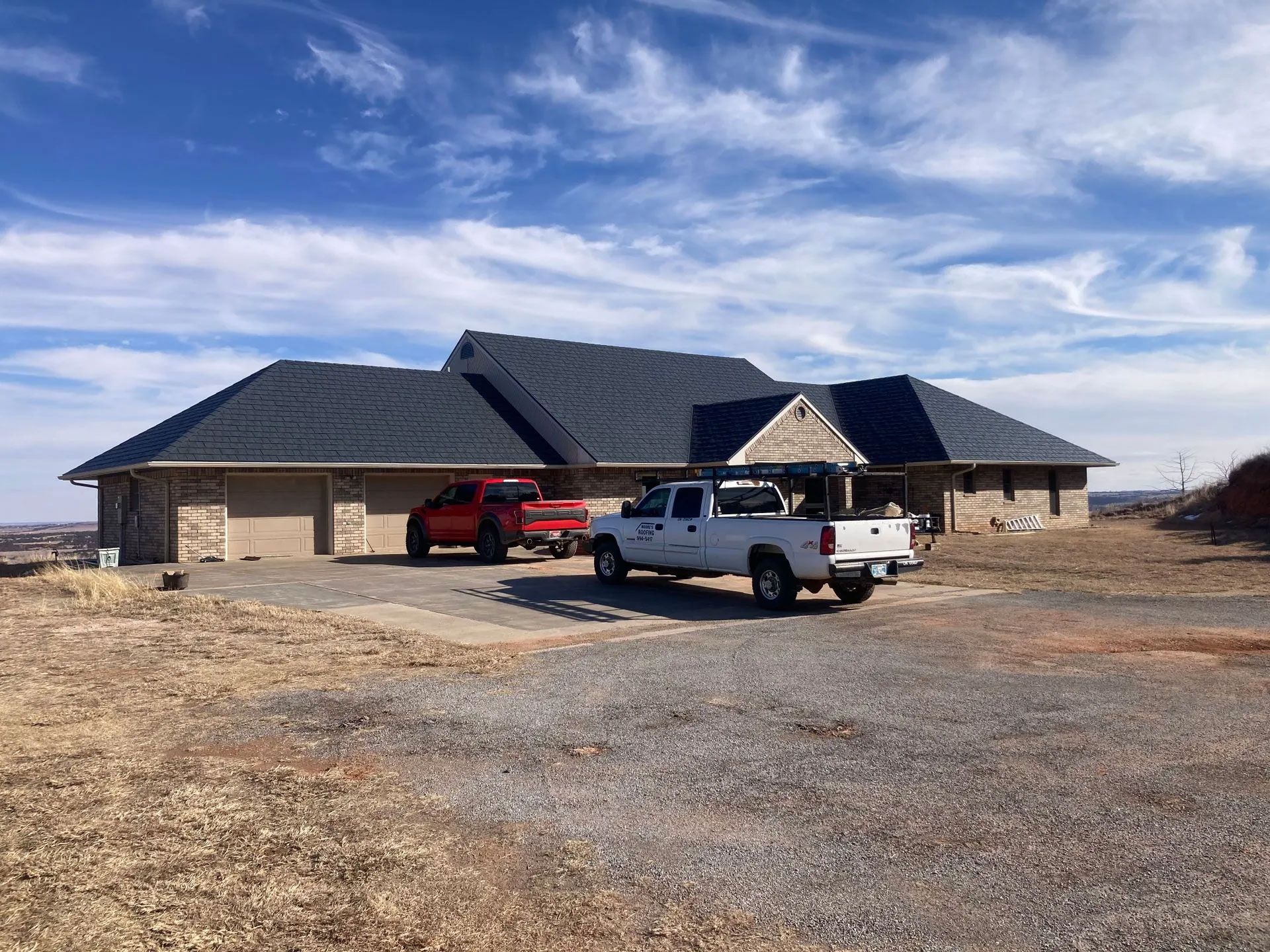 A white truck is parked in front of a large house.