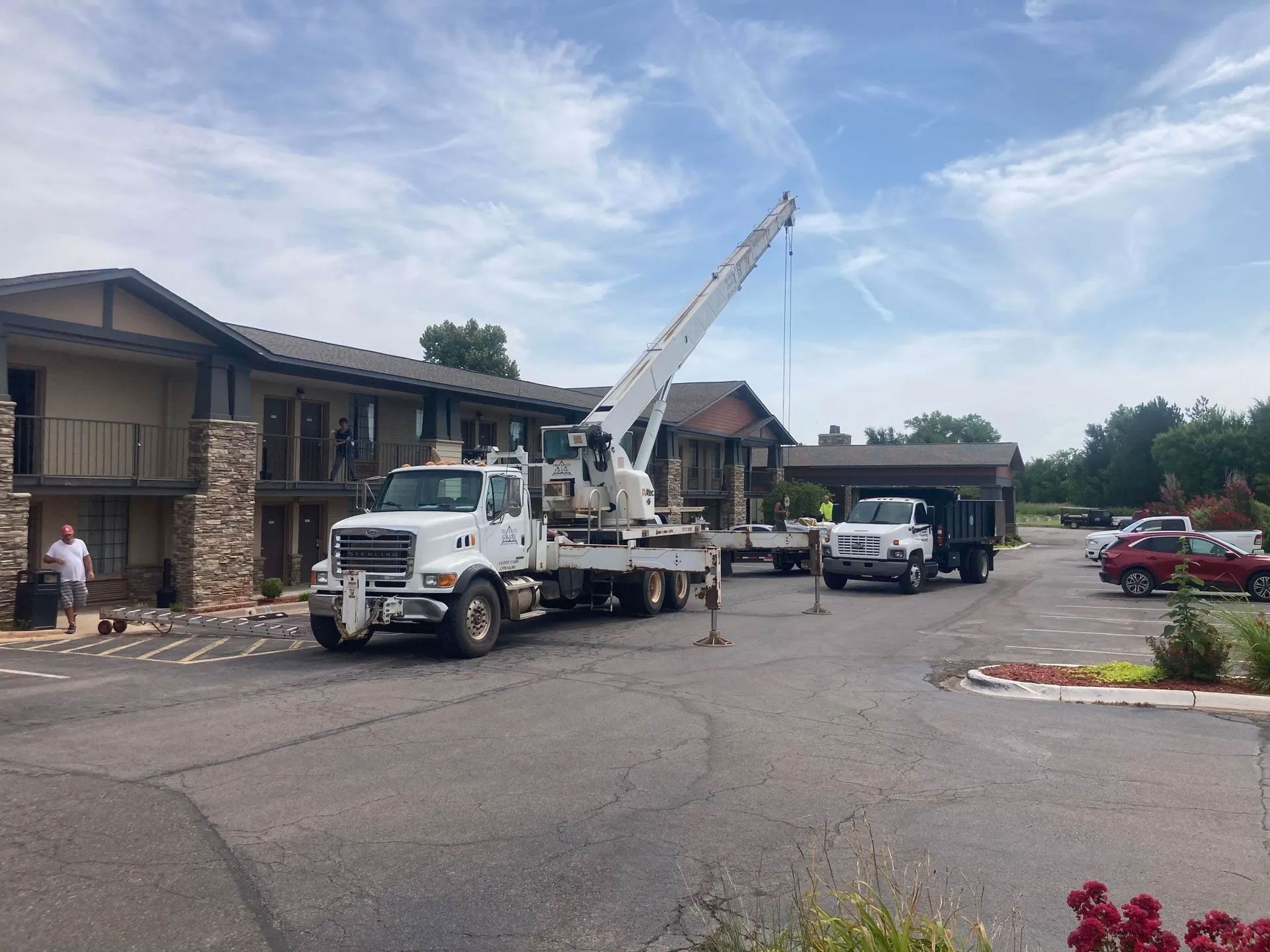 A white truck with a crane on the back is parked in front of a building.