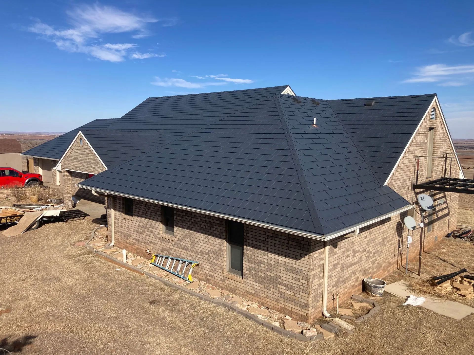 A large brick house with a black roof is being built.