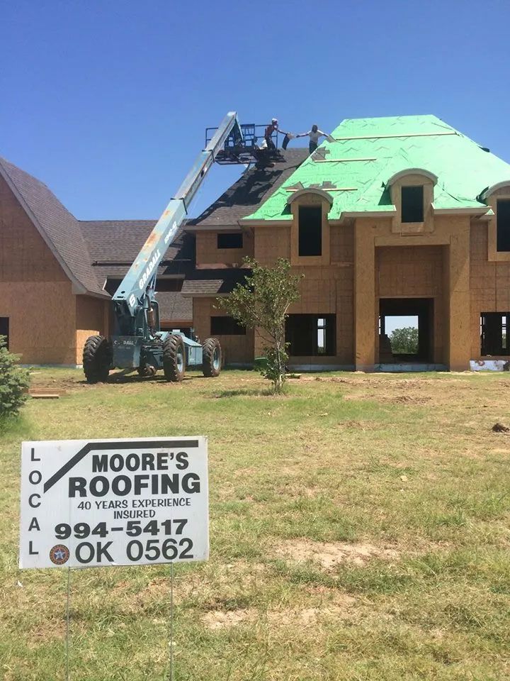 A sign for moore 's roofing is in front of a house under construction