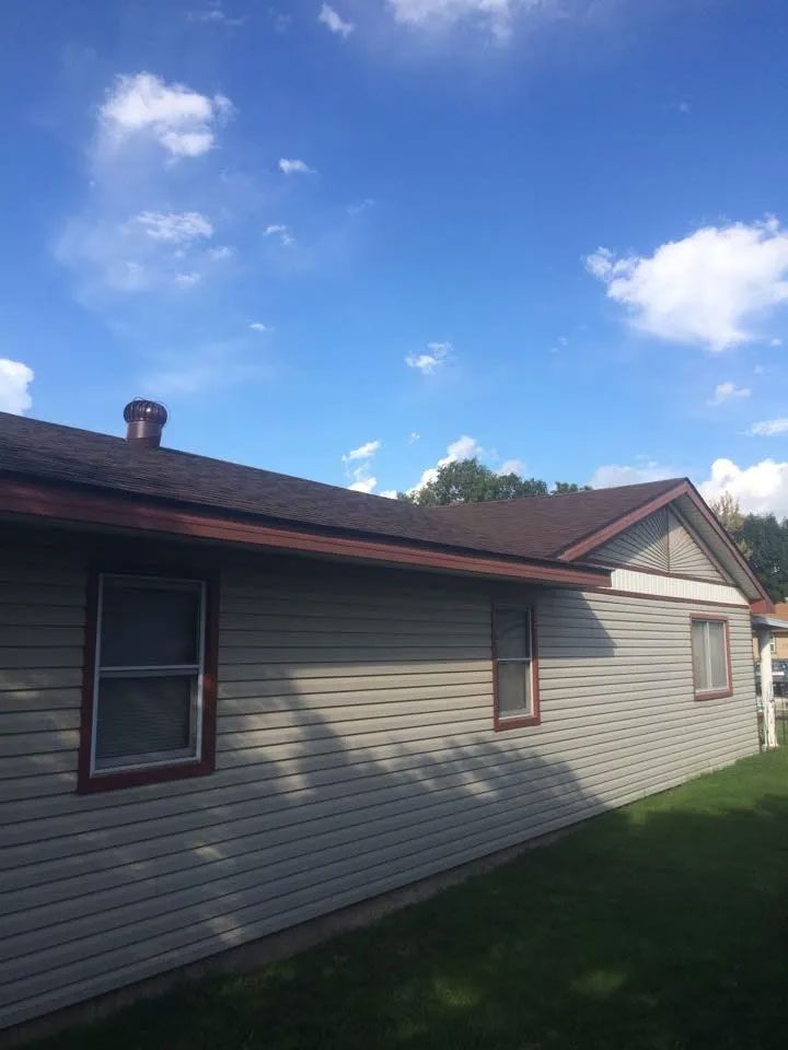 A house with a brown roof and a blue sky in the background.