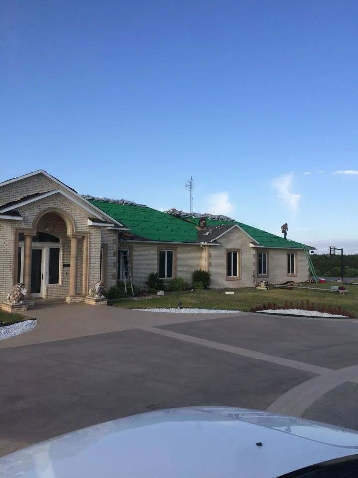 A white house with a green roof is being painted.
