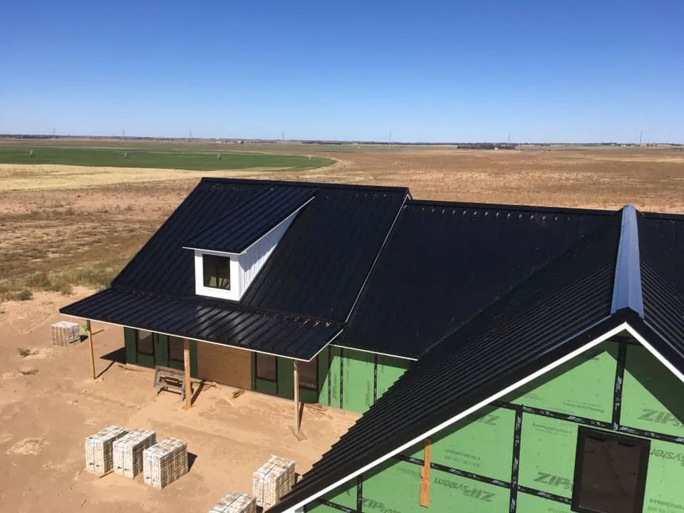 An aerial view of a house under construction with a black roof.