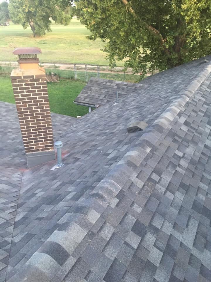 A roof with a chimney on it and a tree in the background.