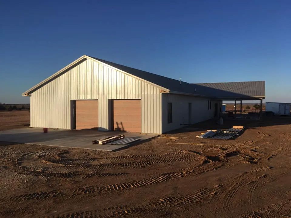 A large white building is sitting in the middle of a dirt field.