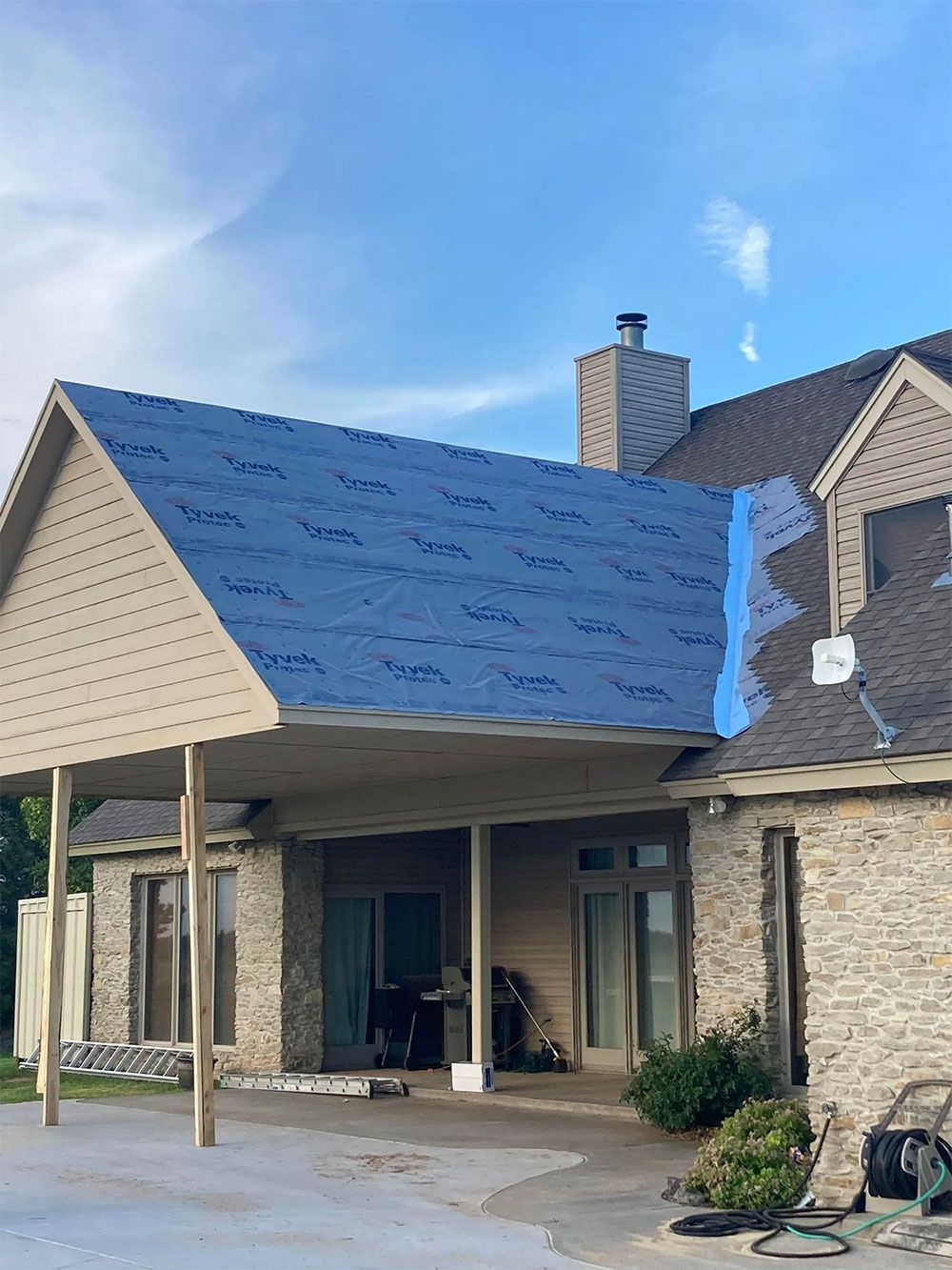 A house with a blue tarp on the roof is being remodeled.