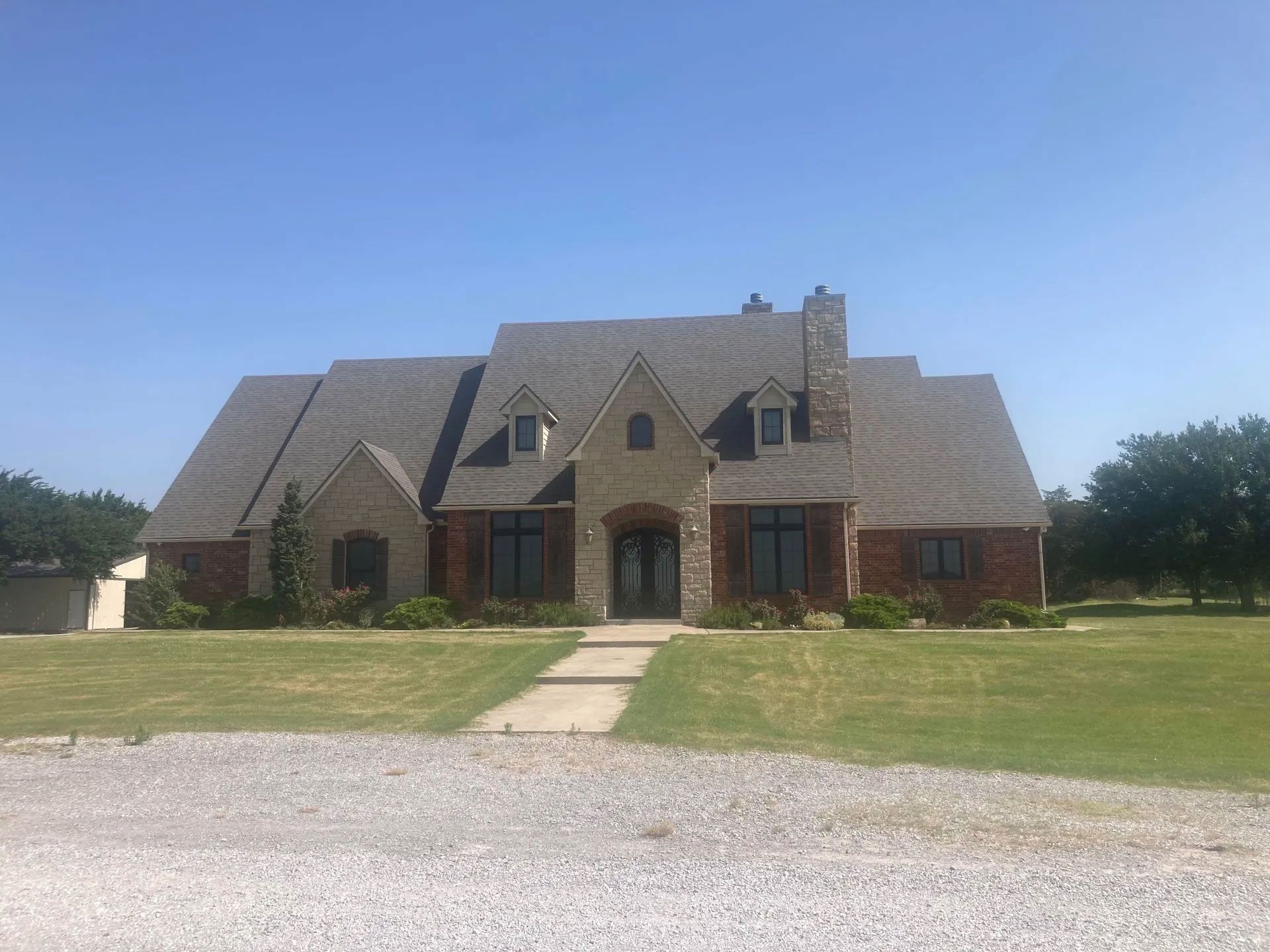 A large brick house with a gray roof and a walkway leading to it