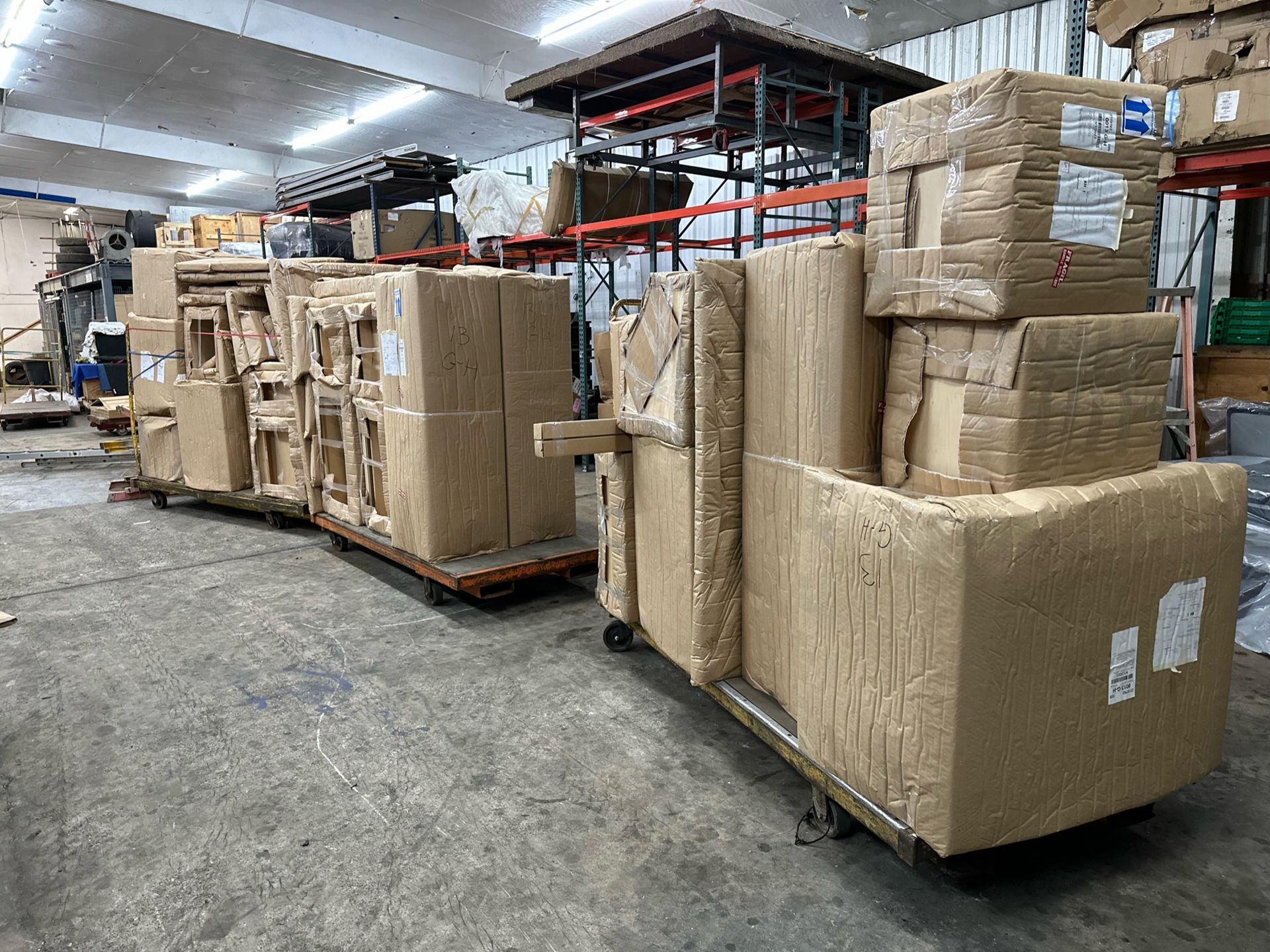 Two large pallets stacked with cardboard-wrapped items sit on a concrete floor in a dimly lit warehouse.