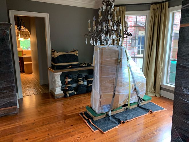 Living room with hardwood floors, chandelier, wrapped furniture, and windows along the right wall
