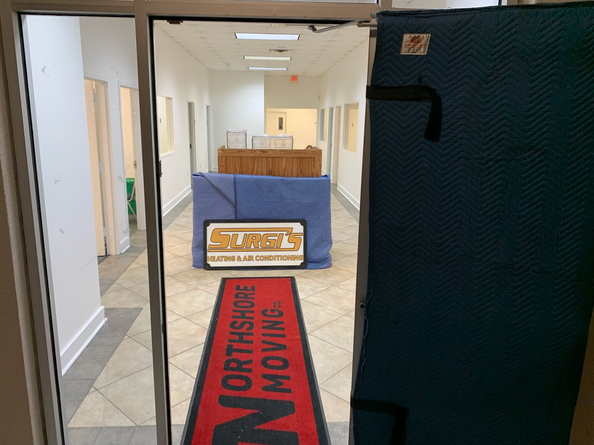 A red Northshore Moving runner on a tiled floor leads toward a doorway containing moving blankets and a branded sign.