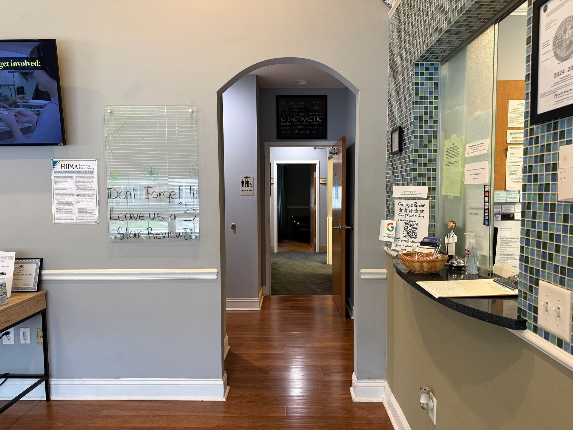 Interior hallway with wood floor, arched doorway, and a reception counter with notes and a coffee station.